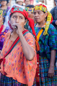 Mayakvinnor i färgglada kläder demonstrerar en av dem röker cigarr.